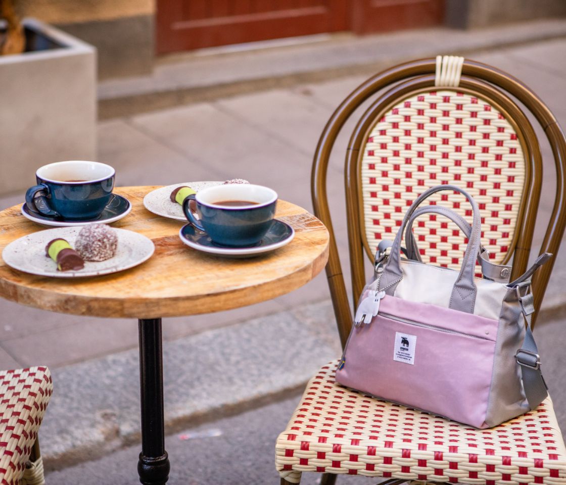 Table with two cups of coffee and pink Moz handbag