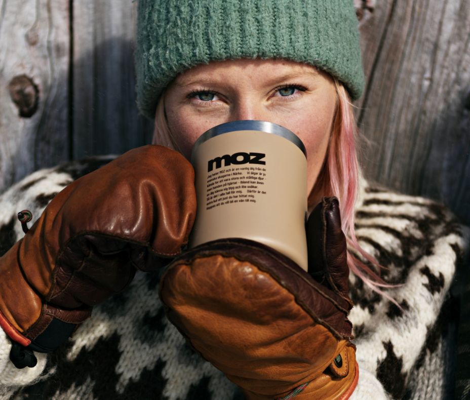Woman in gloves having a coffee in a Moz mug.