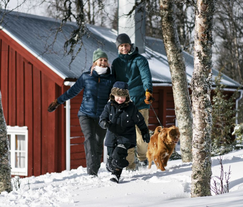 Family playing in the snow with their dog.