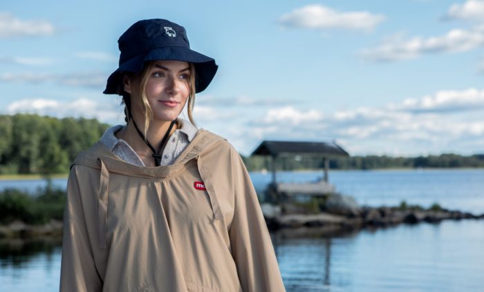 Woman by a lake, wearing Moz jacket and hat.