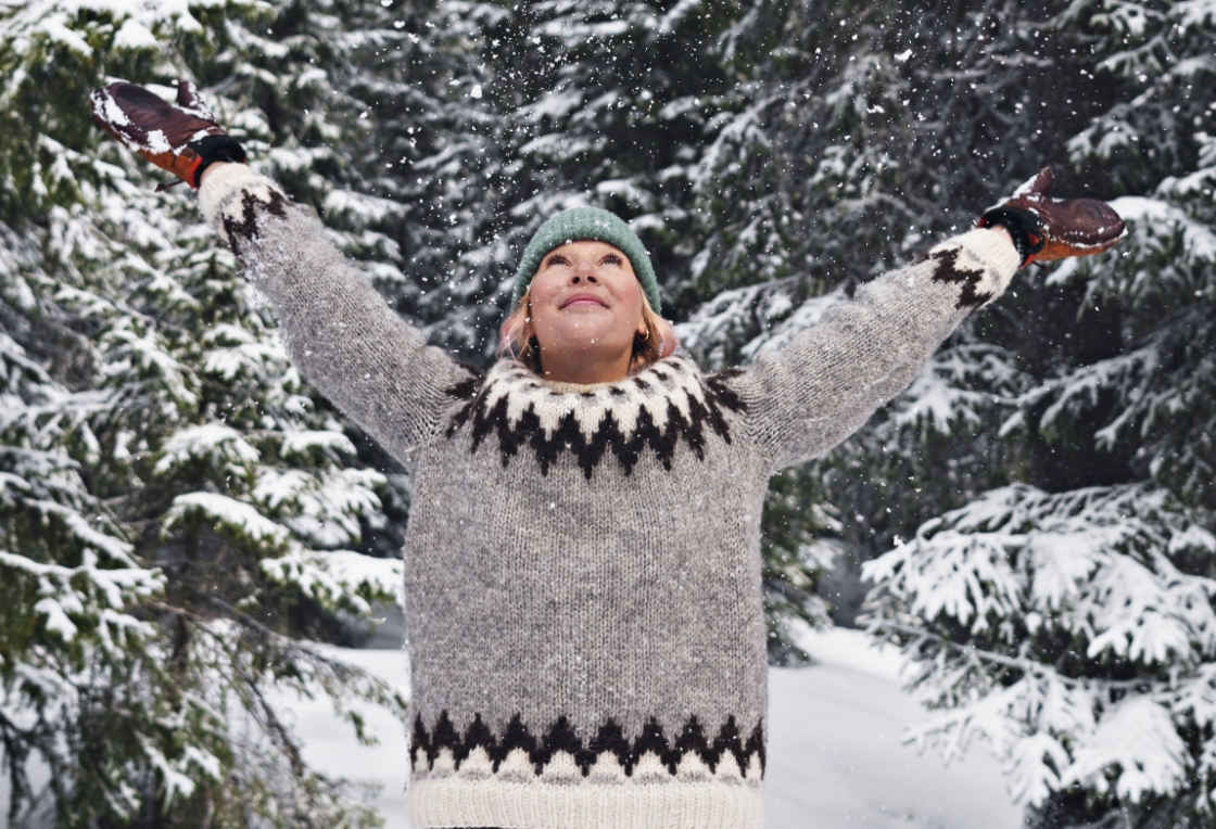 Woman in knitted sweater stretches her arms to the sky