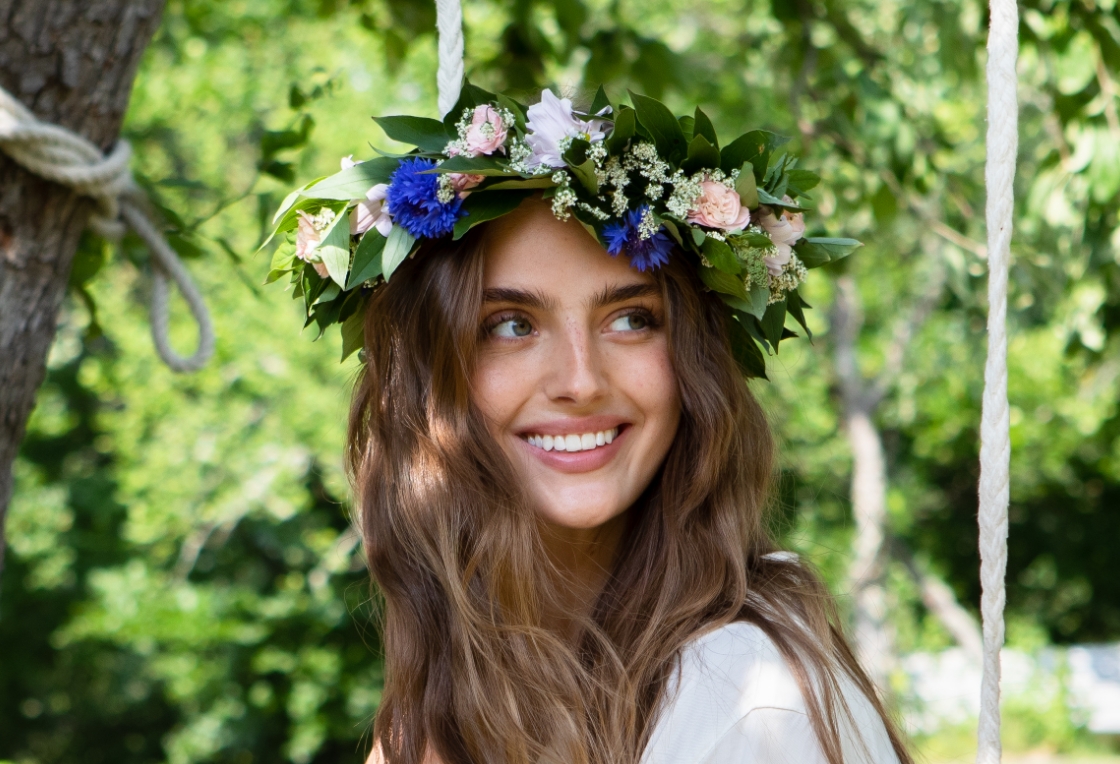 Woman with flower wreath, sitting on a swing