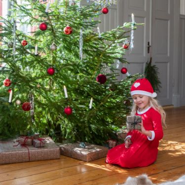 Girl sitting by christmas tree with present