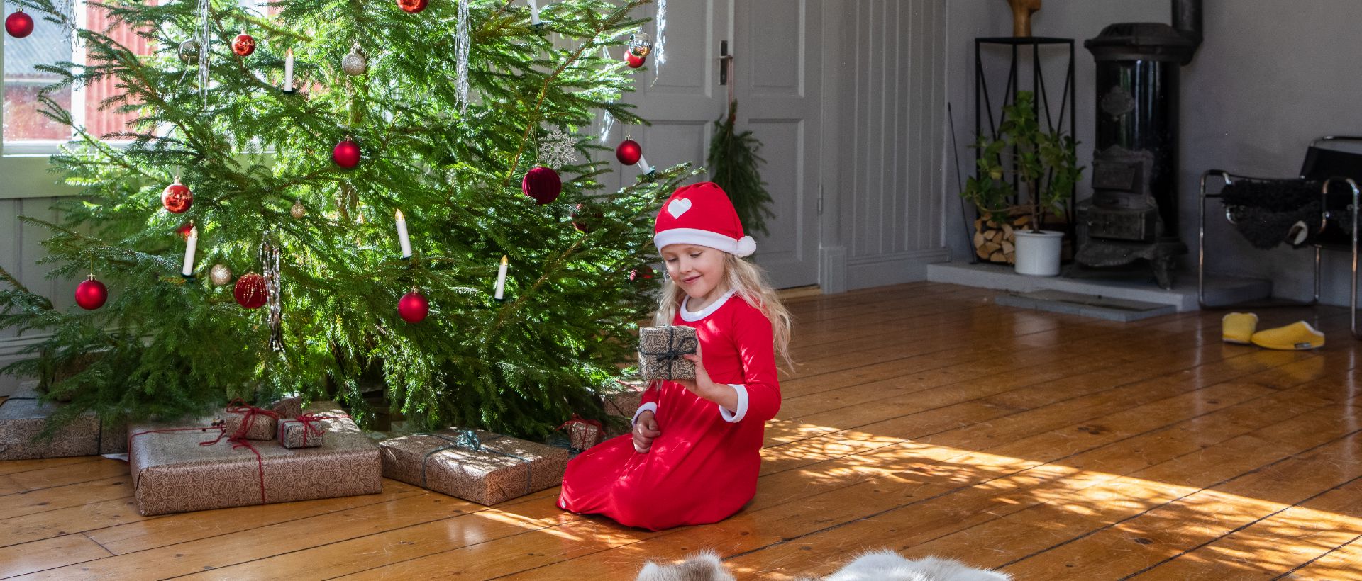 Girl sitting by christmastree with present